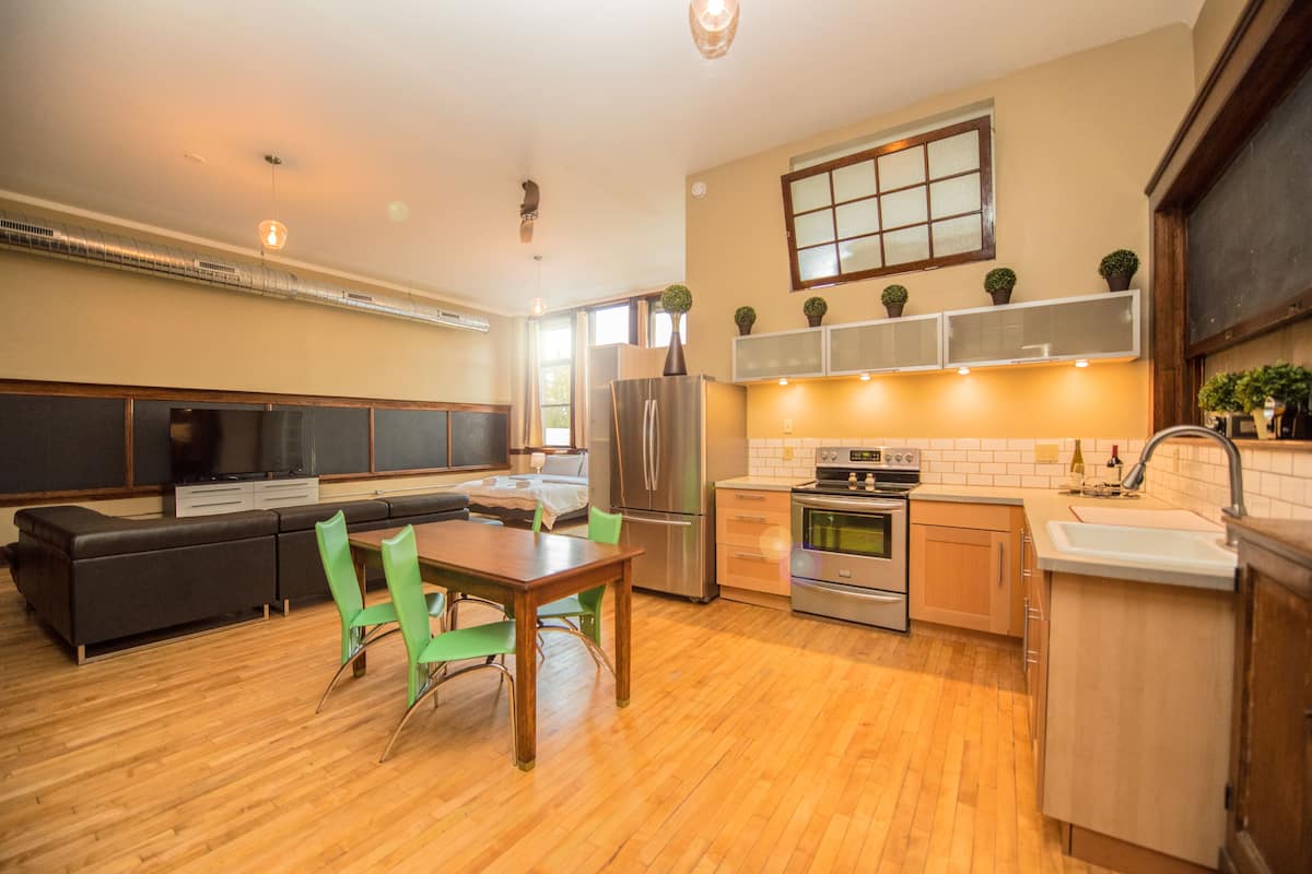 A modern kitchen with a dining area, built-in appliances, and a large window.