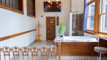 A bathroom with a bathtub, a mirror, and a wooden door.