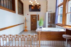 Un baño con bañera, espejo y puerta de madera.