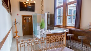 A bathroom with a wooden bed frame, a large mirror, a sink, and a shower. - School 31 Lofts at Colors Studios (Rochester)