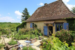 A rustic stone house with a tiled roof, surrounded by a lush garden with various plants and flowers. - authentic rural house of Perigord, charm, calm and comfort 4 * (Lanquais)