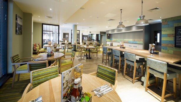 Ein modernes Restaurant mit verschiedenen Essbereichen, Holztischen und -stühlen.