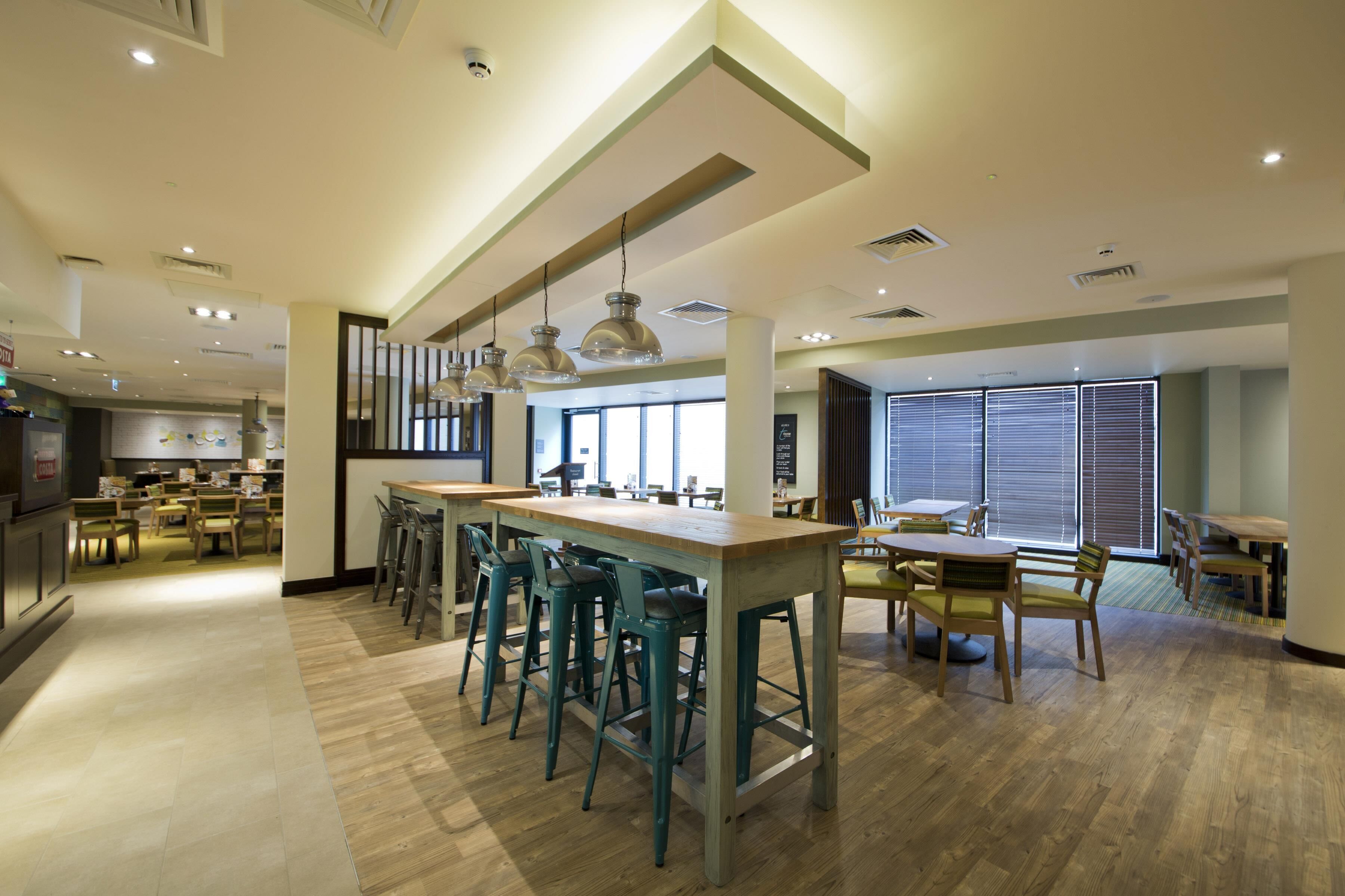 A modern interior with a bar area, seating, and a kitchen in the background.