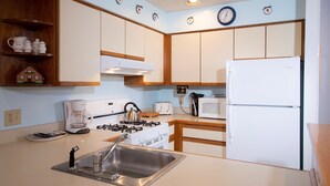 A kitchen with white cabinets, a stainless steel sink, a gas stove, a microwave, and a refrigerator. - Okemo Retreat! Ski-In/Ski-Out Condo (Ludlow)