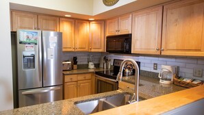 A kitchen with wooden cabinets, stainless steel appliances, granite countertops, and a built-in microwave. - Mountainside Suite! Arcade, Pool, Hot Tub Access (Ludlow)