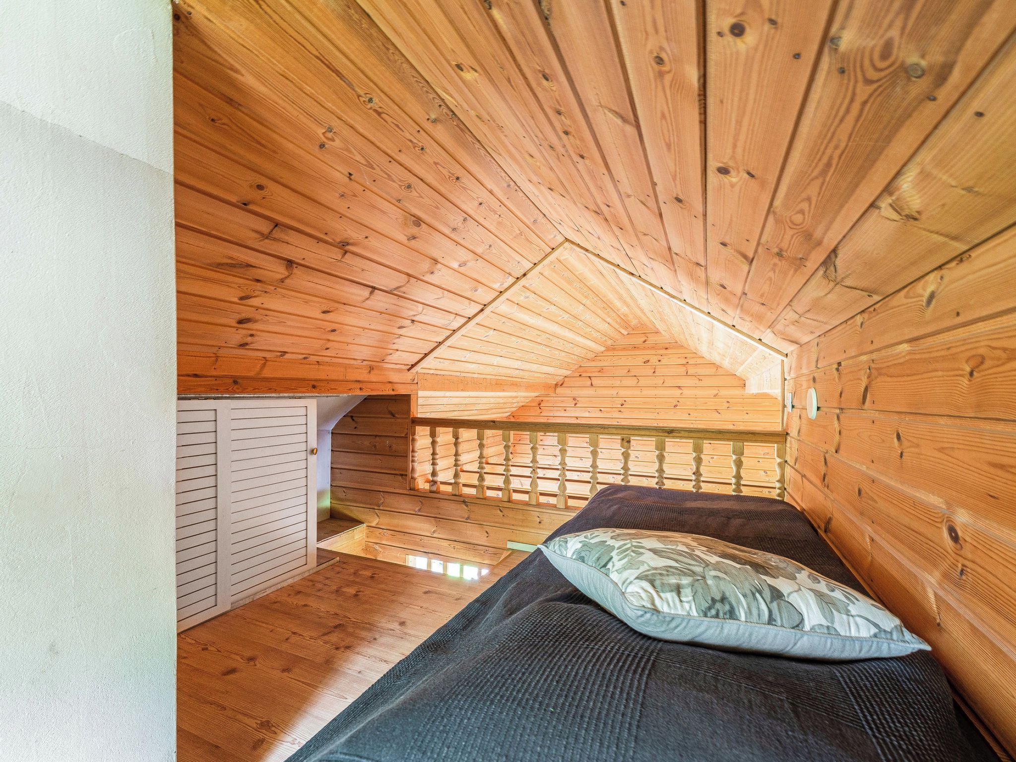 Ein kleines Schlafzimmer im Dachgeschoss mit Holzwänden und schrägen Wänden.
