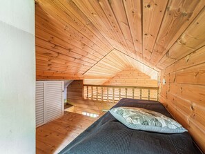 A small attic bedroom with wooden walls and a sloped ceiling. - Kotiranta by Interhome (Petäjävesi)