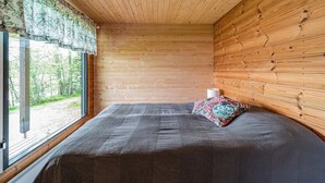 Une pièce de style cabane en bois, avec un lit, une fenêtre et un luminaire au plafond.