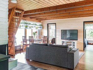 Una sala de estar moderna con sofá, televisión y vigas de madera en el techo.