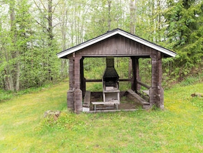 A rustic wooden gazebo with a fireplace, surrounded by a forested area. - Kotiranta by Interhome (Petäjävesi)