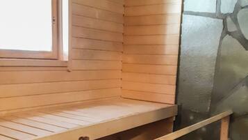 Una sala de sauna con bancos de madera, una pared de piedra y una ventana.