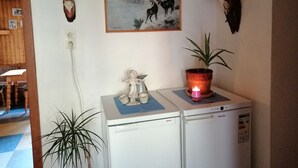 A room with a Bosch refrigerator, a painting of mountain goats, and several animal skulls on the wall.