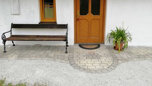 A bench outside a building with a wooden door and a window.