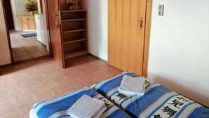 A room with a bed, a wooden wardrobe, a door, and a small kitchenette area.