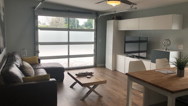 Ein modernes Wohnzimmer mit Sofa, Couchtisch und Essbereich mit Tisch und Stühlen.