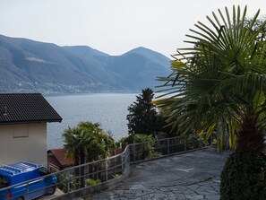A coastal road with a blue van parked on the left, leading to a building with a tiled roof.