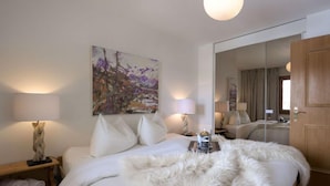 Une chambre d’hôtel avec un grand lit, deux lampes de chevet, un tableau au mur et un miroir qui reflète la pièce.