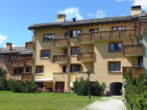 A multi-story building with balconies and a paved pathway leading to the entrance. - Chesa Ludains 8 by Interhome (St. Moritz)