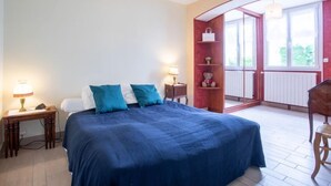 A bedroom with a large bed, bedside tables, a red shelving unit, and a view of the outdoors through a glass door. - Villa Hélios by Interhome (Cabourg)