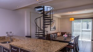 A modern kitchen with granite countertops, a built-in sink, and a spiral staircase. - San Pedro Hotel 5ta Avenida (Playa del Carmen)