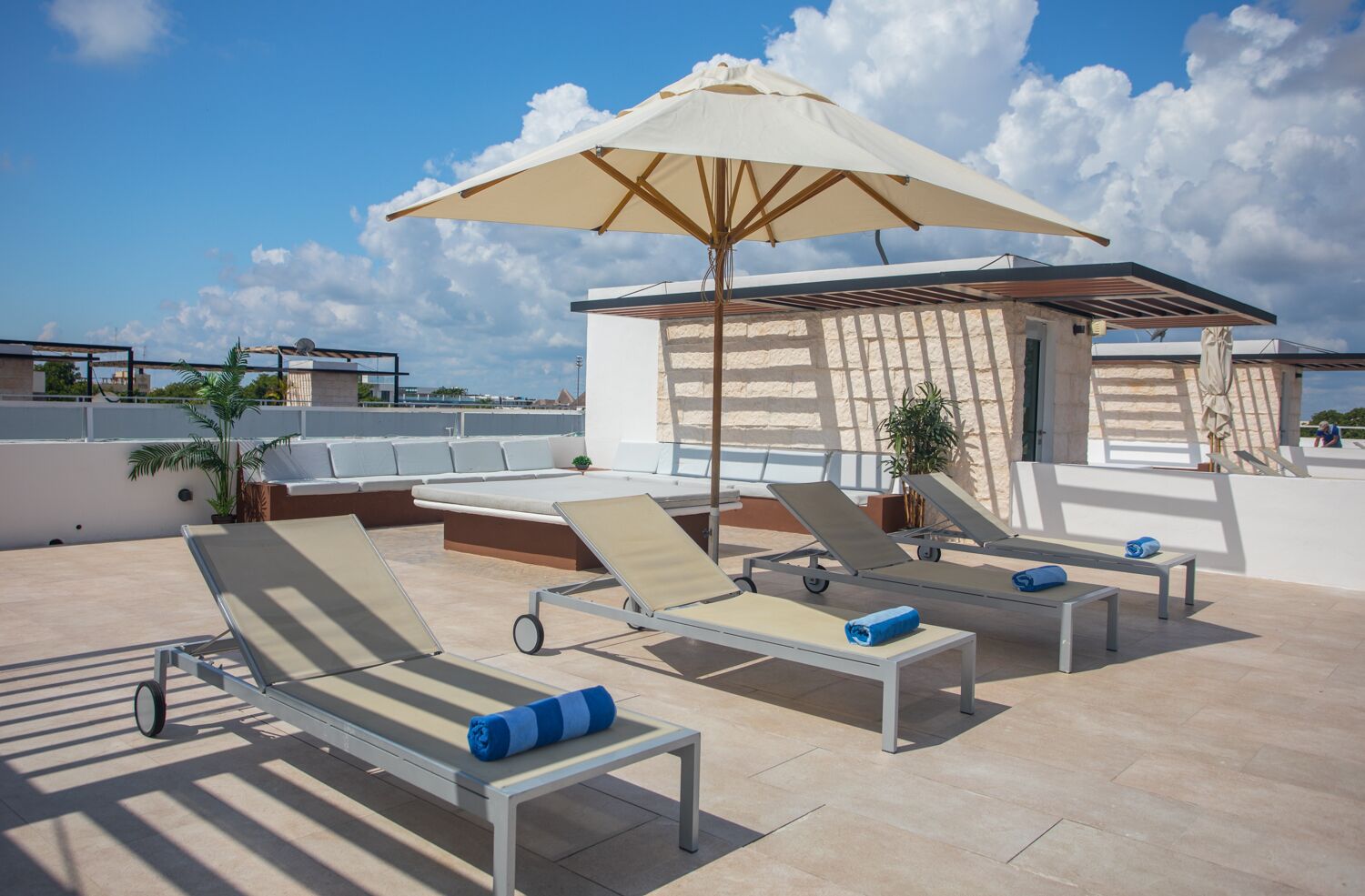 Un espace de détente aménagé sur le toit, avec des chaises longues, un grand parasol et un petit coin salon.