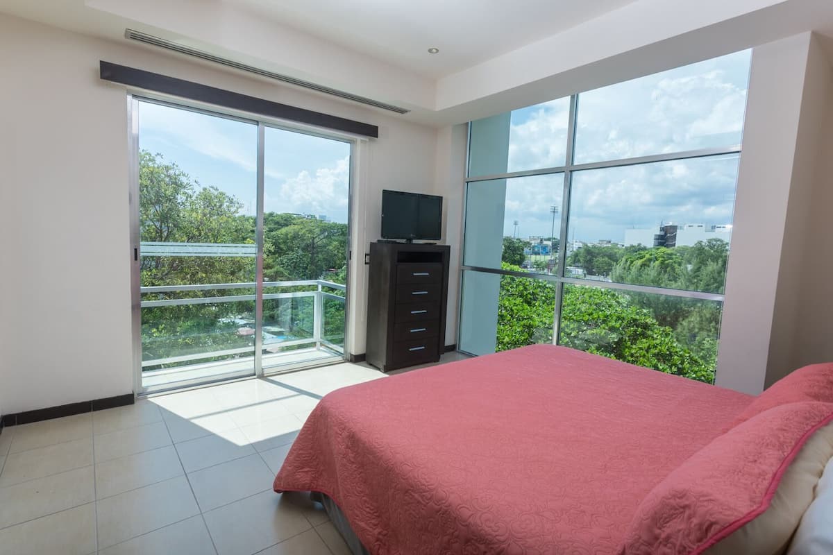 Ein Schlafzimmer mit großem Fenster, einem Bett und einem TV-Schrank.
