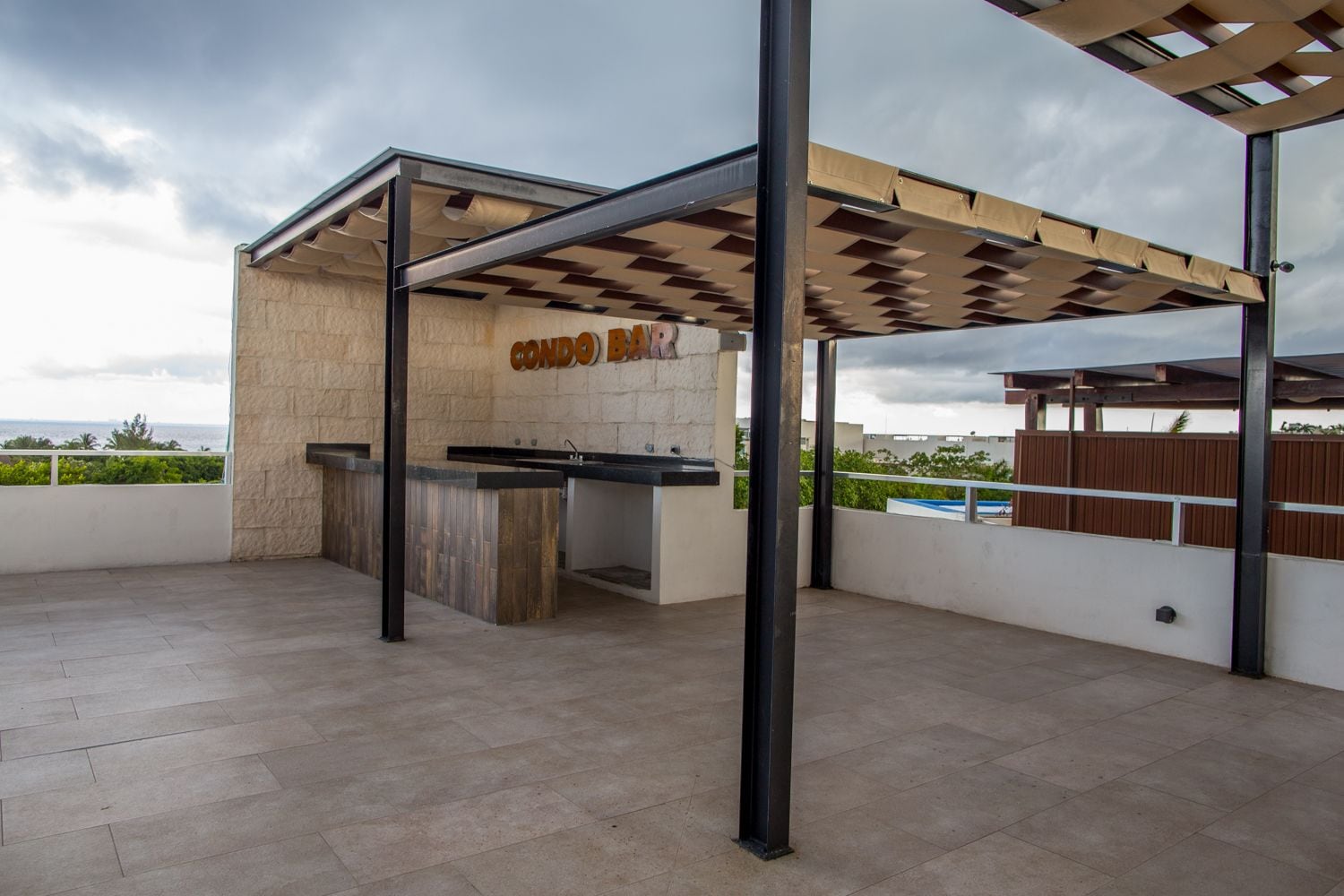 Un espace extérieur abrité comprenant un coin cuisine, un mur en pierre et une vue sur la mer.