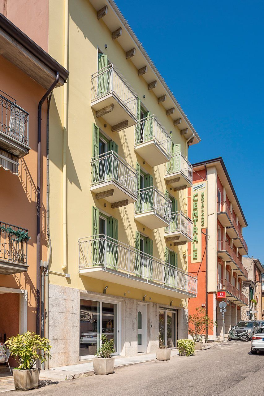 A multi-story hotel with balconies, a central entrance, and a clear blue sky.