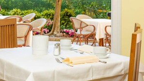 Une table dressée pour le repas, avec une nappe blanche, un pichet, des salières et des poivrières, et une serviette pliée.