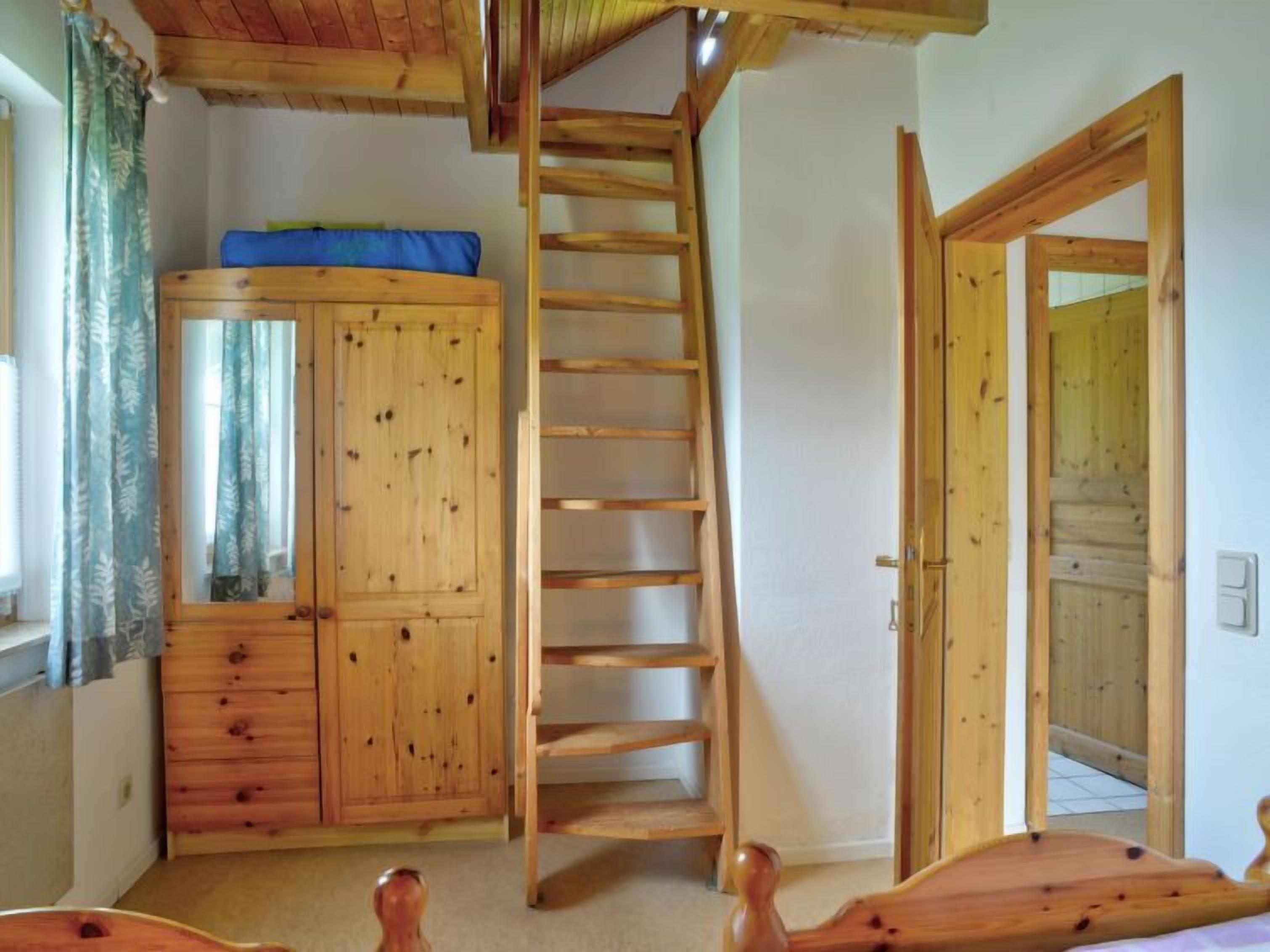 Ein Zimmer mit Holzboden, einem Schlafplatz in der Esse und einer Leiter zum Erker.