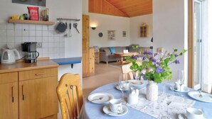A dining area with a table set for four, a kitchen area with a coffee maker, and a living room with a sofa and a dining table. - Solling by Interhome (Uslar)