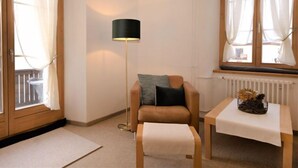 Una habitación acogedora con una silla, una mesita, una lámpara de pie y un ventanal con cortinas.