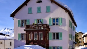 Un edificio de varios pisos con un balcón, nieve en el techo y un cielo despejado.