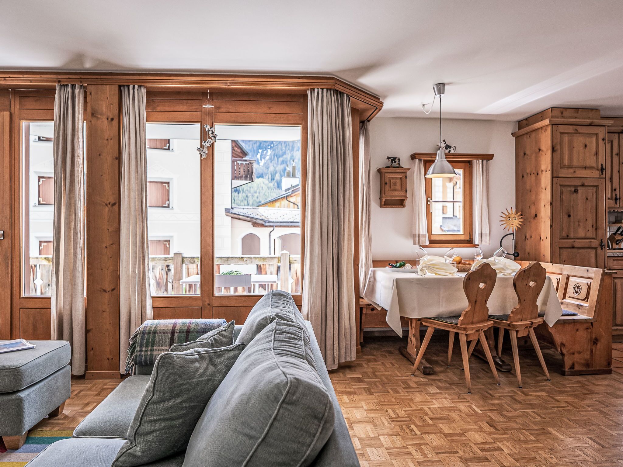 Ein gemütliches Wohnzimmer mit einer Couch, Holzboden und großen Fenstern.