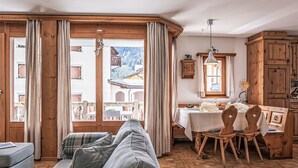 A cozy living room with a sofa, wooden floor, and large windows. - Chesa Mezzaun by Interhome (Zuoz)