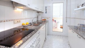 A modern kitchen with white cabinets, a black stovetop, and a granite countertop.