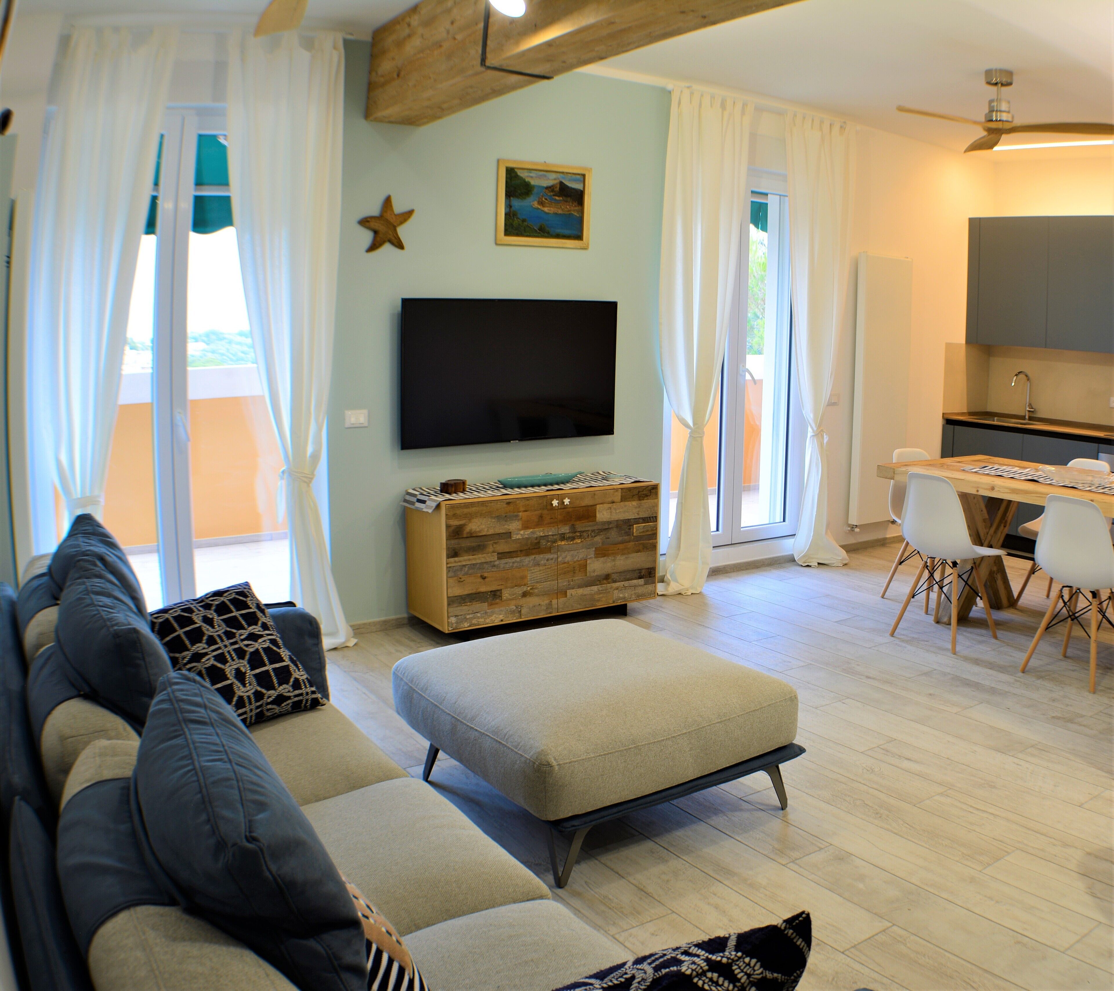 A modern living room with a sofa, ottoman, and a flat-screen TV.