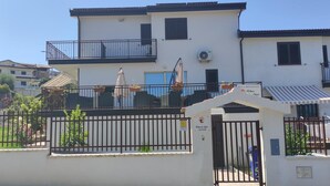 A two-story building with a gated entrance, outdoor seating area, and a sign indicating a restaurant. - Alba De Mar (Roseto Capo Spulico)