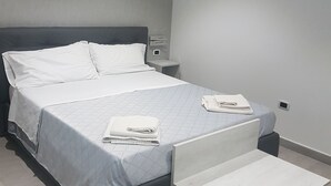 A modern bedroom with a bed, bedside table, and a small bench. - Alba De Mar (Roseto Capo Spulico)