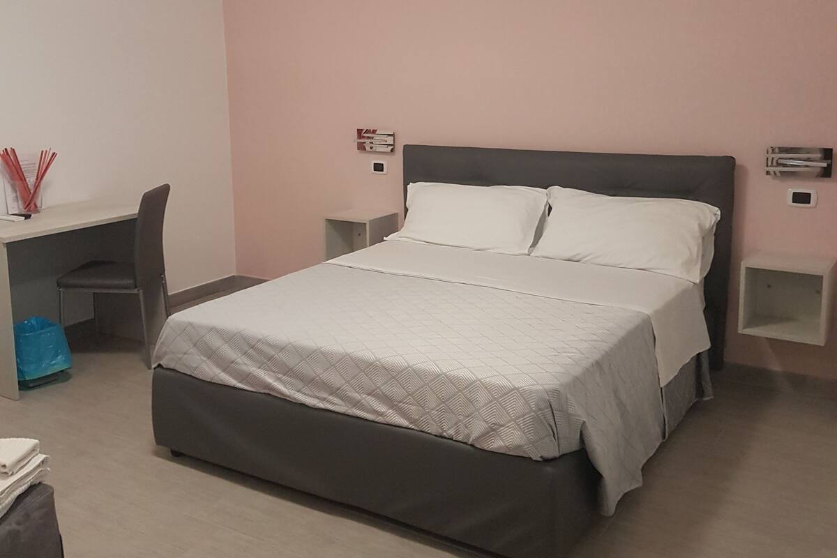 Un dormitorio ordenado con cama, escritorio y silla.