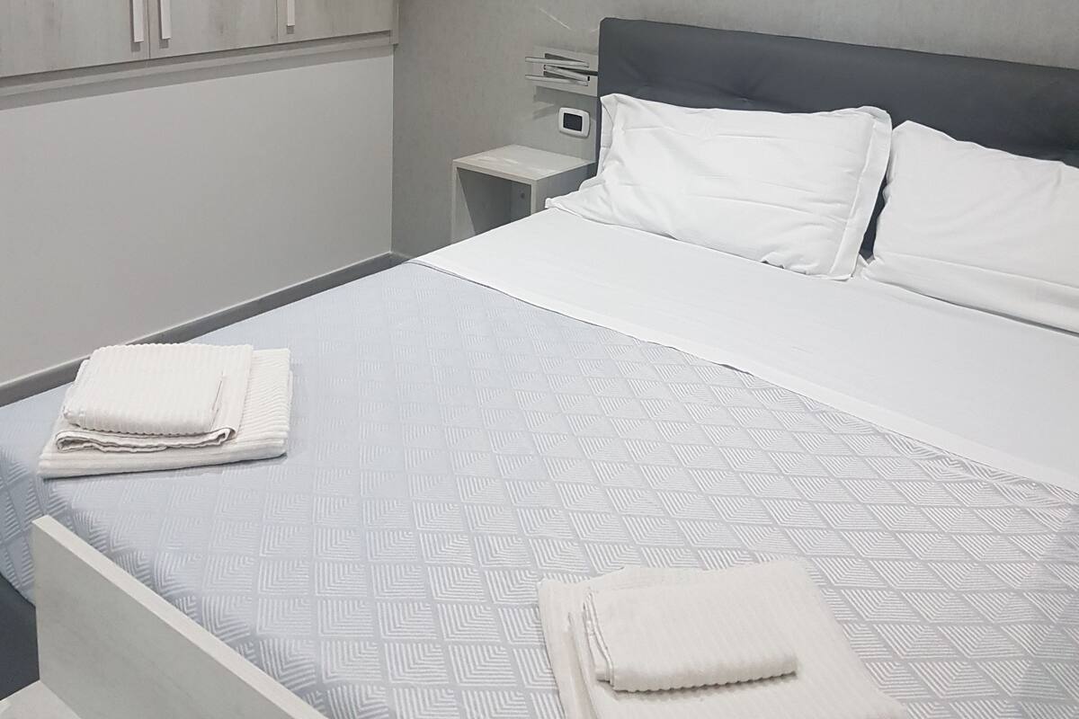 Una habitación de hotel moderna con una cama grande, una mesita de noche y un armario.