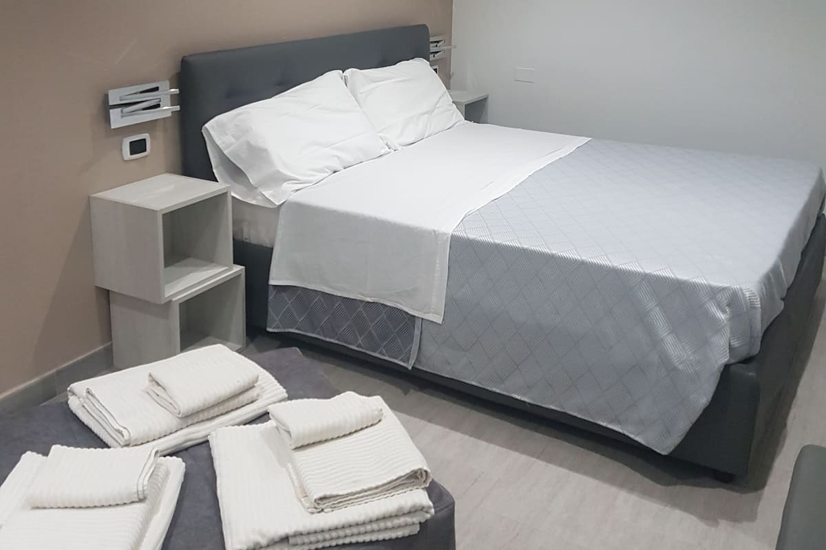 Una habitación de hotel moderna con cama, mesitas de noche y una pequeña zona de estar.