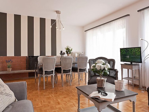 A modern living room with a dining area, a television, and a fireplace.