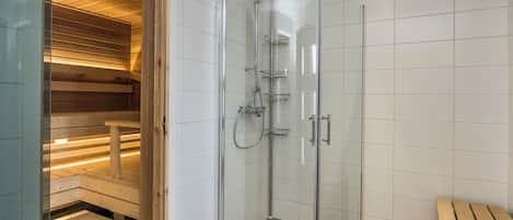 A glass-enclosed shower with a bench and a wooden sauna area.