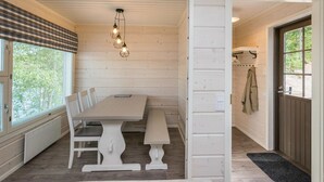 Una habitación acogedora con detalles de madera, un ventanal con persianas, un banco, una mesa y una lámpara colgante.