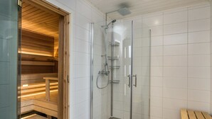 Un espacio de ducha moderno con cabina de vidrio, bancos de madera y suelo de baldosas.