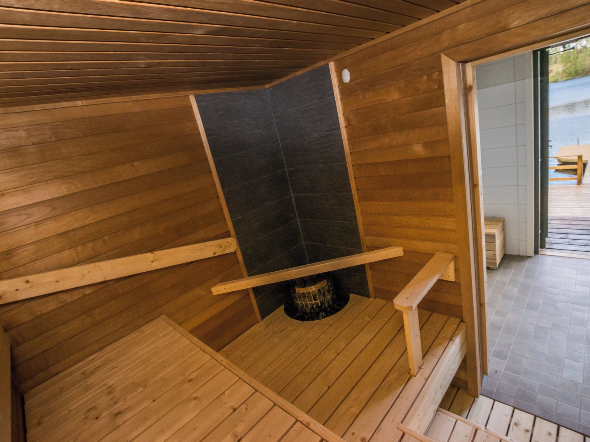 Eine Sauna mit Holzwänden und Fliesenboden, einer Sitzbank und einem kleinen Tisch.