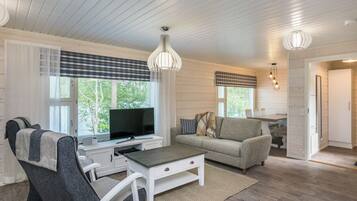 A modern living room with a television, sofa, and a dining area.