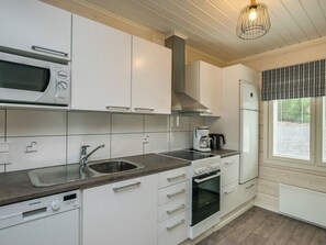 A modern kitchen with white cabinets, a stainless steel sink, a microwave, a stove, and a refrigerator. - Tähtiranta by Interhome (Valkeala)