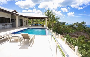 A pool area with lounge chairs, a covered seating area, and a view of the ocean. - Villa Lomamar (Las Terrenas)